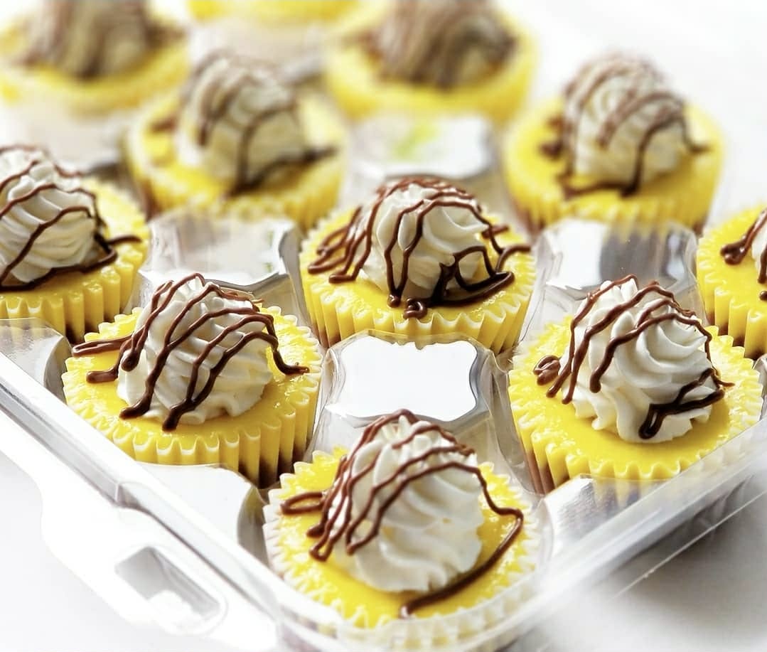 Bright lemon mini cheesecakes with piped cream and chocolate drizzle